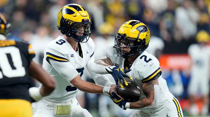 Michigan quarterback J.J. McCarthy, left, hands the ball off to running back Blake Corum.